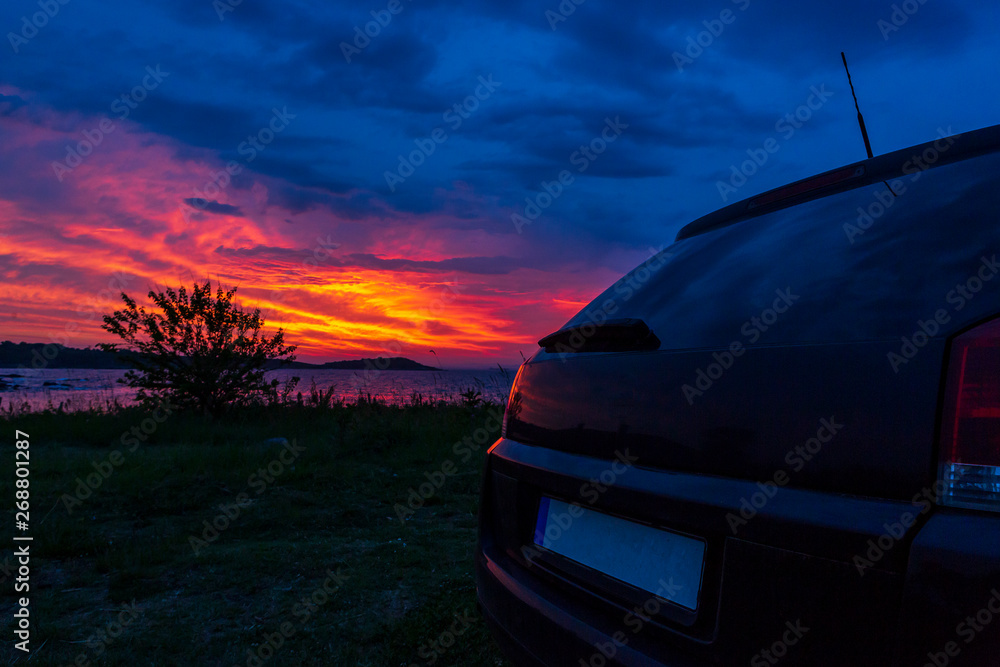 Obraz premium black car on the beach on a beautiful sunset background. sea sunrise view from car on the beach. ocean vacation and ocean holiday.