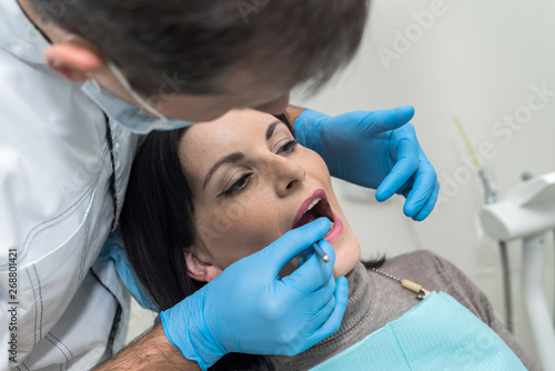 Doctor inspecting patient s teeth with mirror close up