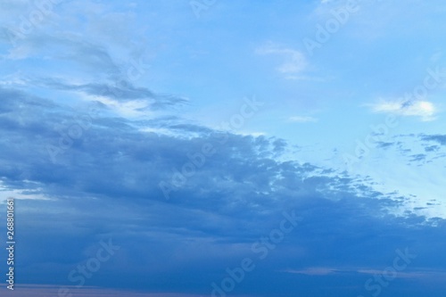 The firmament is naturally divided diagonally. In the lower left corner of the thick blue clouds. The upper right corner is occupied by a bright blue sky with a small amount of white light clouds.