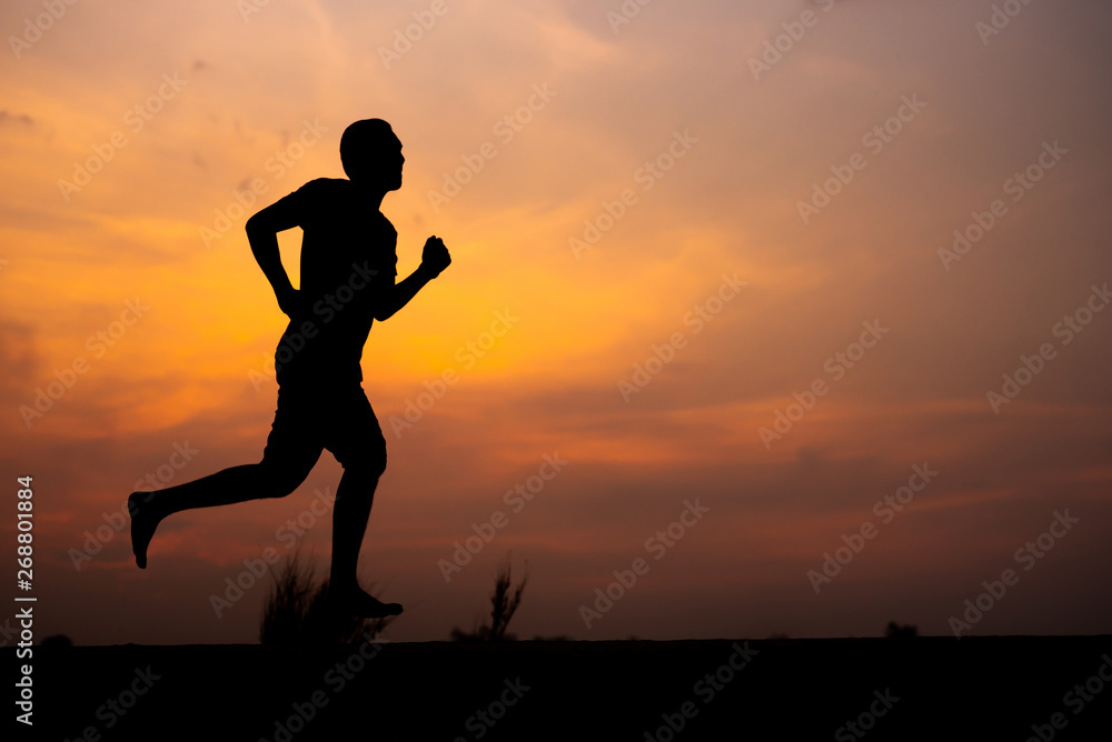 Man running alone at beautiful sunset in the road at park . Summer sport and freedom concept. Athlete training on dusk. - Image