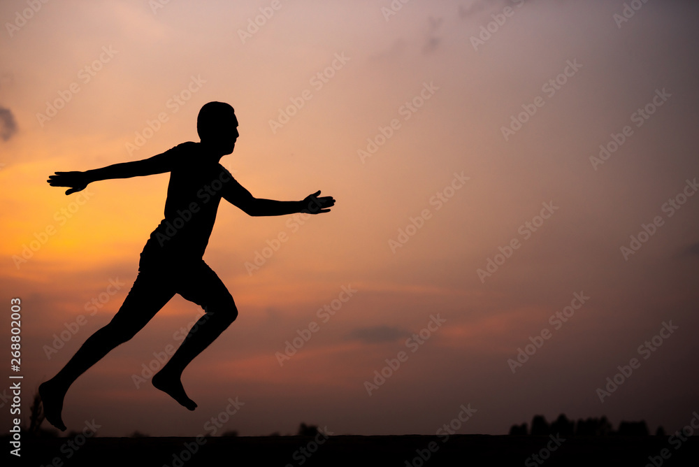 Fototapeta premium Man running alone at beautiful sunset in the road at park . Summer sport and freedom concept. Athlete training on dusk. - Image
