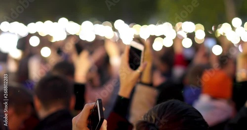 A blurred view of many bright smartphone flashlights filling outdoors photo