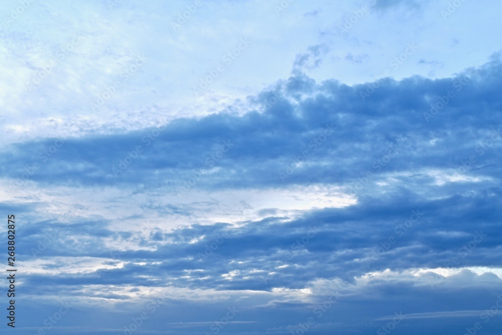 Blue sky with diagonal stripes of blue clouds. From left to right up. Photo with a blue gradient, from light to dark. Blue sky with diagonal stripes of blue clouds. From left to right up. Photo with a blue gradient, from light to dark.