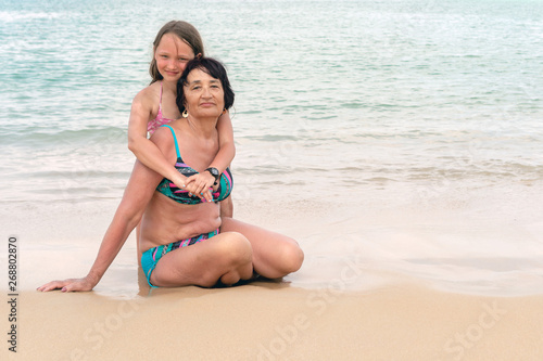 Grandmother hugs granddaughter on a sunny day. Happy senior woman smiling. Concept of sunny and happy summer.