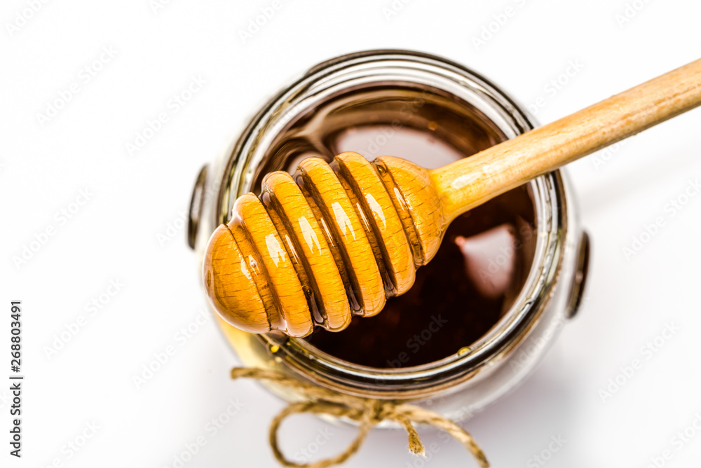 Honey dipper and glass jar of honey, top view Honey dipper and glass jar of honey, top view