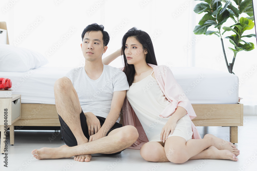 Sexy couple in pajamas sit on floor in bedroom.. Sexy couple in pajamas sit on floor in bedroom..