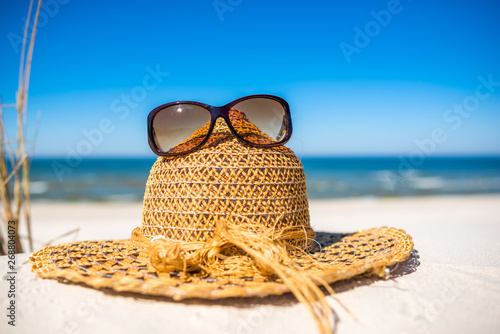 Fototapeta Naklejka Na Ścianę i Meble -  Summer beach accessories - sun hat and sunglasses on sand. Summer vacation background, Baltic Sea, Poland.