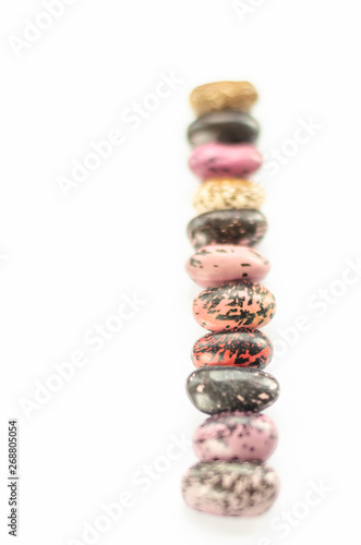 Vertical row of multicolored beans on white background. Eleven raw kidney beans. Close-up