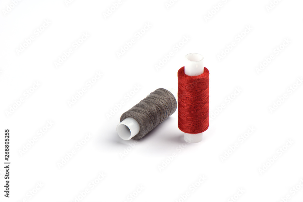 Cotton red and gray threads on the plastic sleeve for the sewing machine. Cotton red and gray threads on the plastic sleeve for the sewing machine.