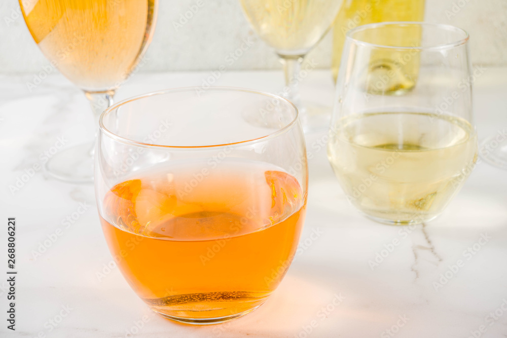 Trendy orange wine, with white wine in different glasses, white concrete background copy space Trendy orange wine, with white wine in different glasses, white concrete background copy space