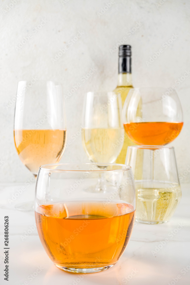 Trendy orange wine, with white wine in different glasses, white concrete background copy space Trendy orange wine, with white wine in different glasses, white concrete background copy space
