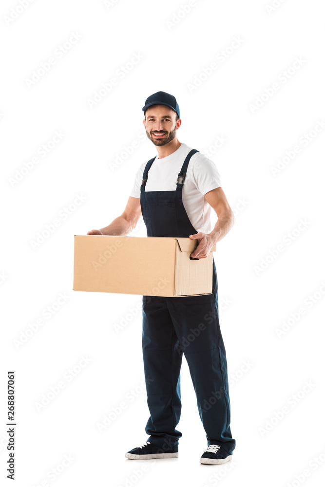 smiling delivery man in overalls holding cardboard box and looking at camera isolated on white smiling delivery man in overalls holding cardboard box and looking at camera isolated on white