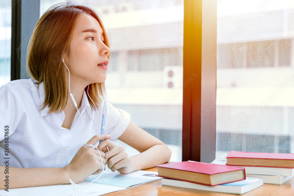 cute young teen Asian university girl in uniform reading book in library cute young teen Asian university girl in uniform reading book in library