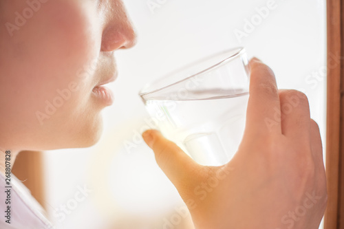 closeup girl drinking clean room temperature water in summer hot day