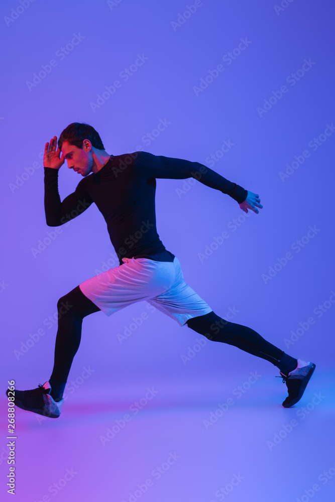 Fototapeta premium Full length portrait of a fit sportsman running isolated