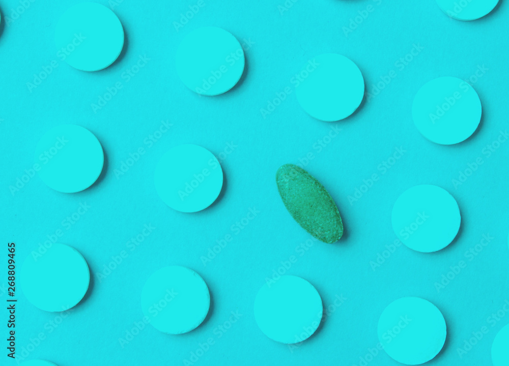 Herbal pill among white chemical pills. Your choice. Background of the group of pills. Medical concept. Duotone effect.