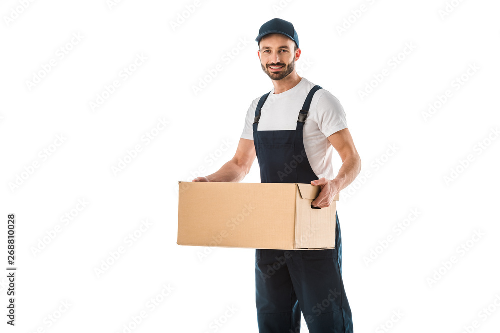 handsome delivery man in overalls holding cardboard box and smiling at camera isolated on white handsome delivery man in overalls holding cardboard box and smiling at camera isolated on white