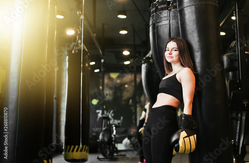 A tired young sport woman in boxing gloves  resting after  heavy boxing training with punching bag. © splitov27