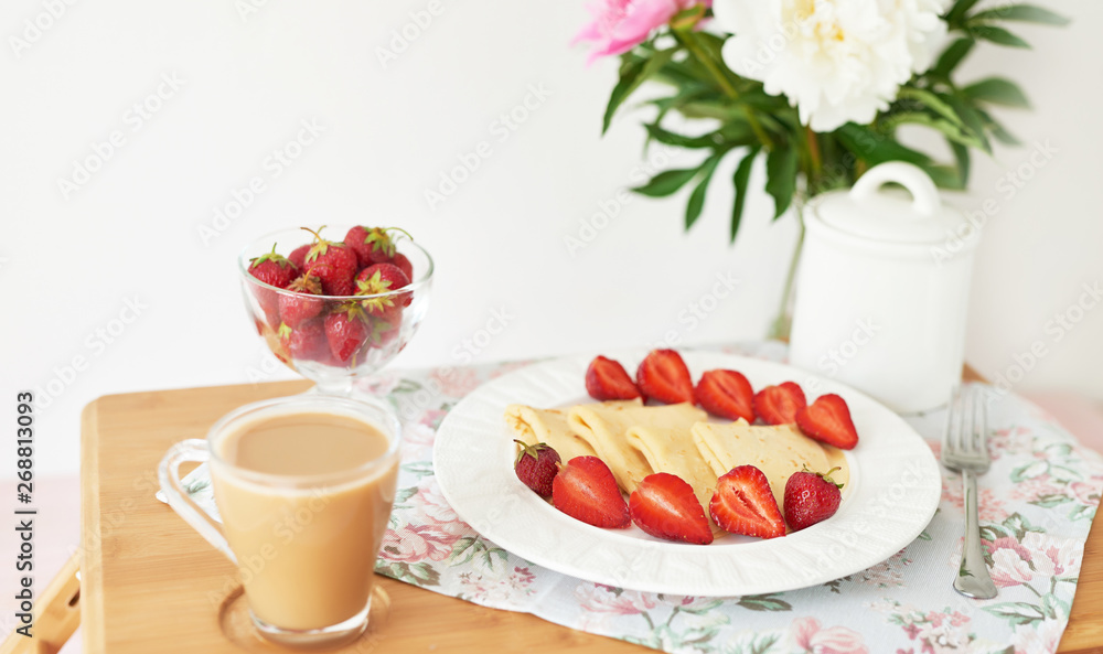 pancakes with strawberries and coffee on the table near a vase with peonies on a white background pancakes with strawberries and coffee on the table near a vase with peonies on a white background