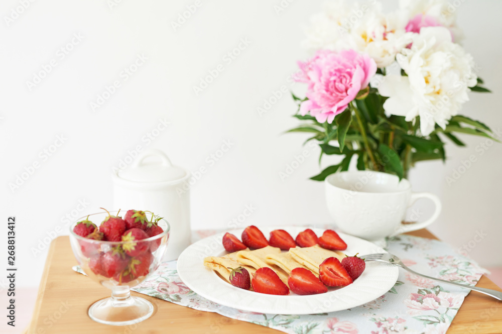 pancakes with strawberries and coffee on the table near a vase with peonies on a white background pancakes with strawberries and coffee on the table near a vase with peonies on a white background