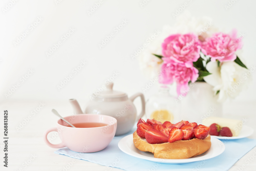 strawberry with croissant and tea on the table near a vase with peonies on a white background strawberry with croissant and tea on the table near a vase with peonies on a white background