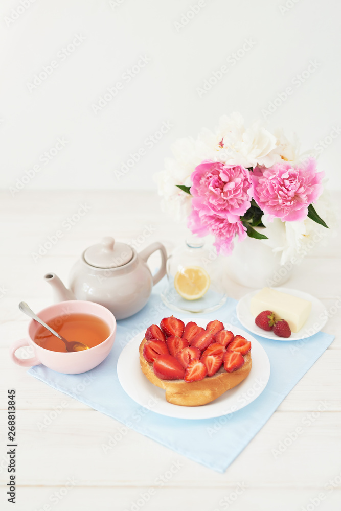 strawberry with croissant and tea on the table near a vase with peonies on a white background strawberry with croissant and tea on the table near a vase with peonies on a white background