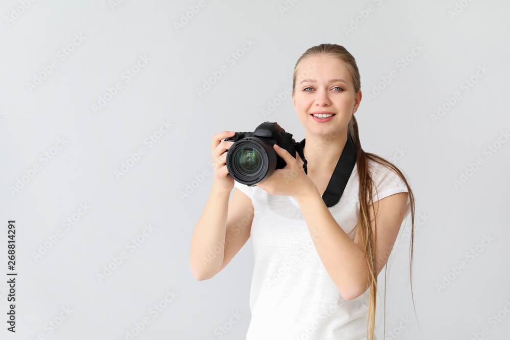 Young female photographer on light background Young female photographer on light background