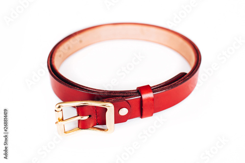 leather belt on a white background. The belt is twisted in a circle. gold hardware.