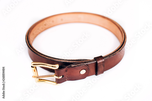 leather belt on a white background. The belt is twisted in a circle. gold hardware.