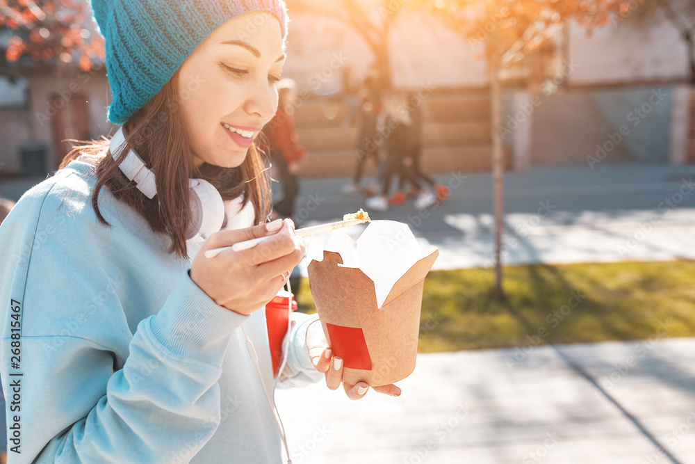 Obraz premium Happy asian woman eaiting takeaway noodles with chopsticks. Chinese fast food concept