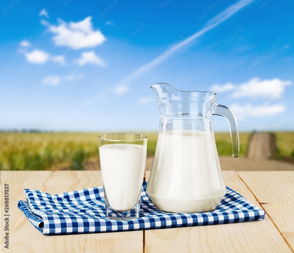 Glass of milk and jug on blurred background Glass of milk and jug on blurred background
