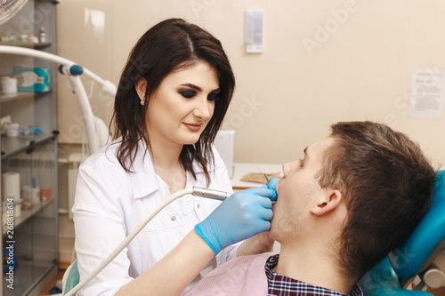 Female doctor doing dental work to the male patient in the dental room