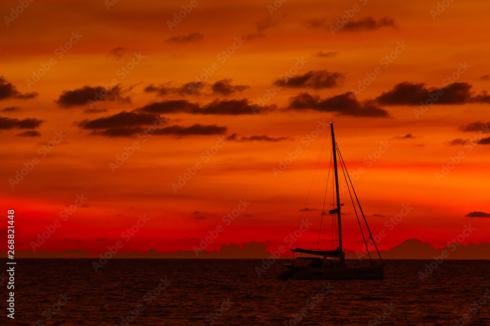 Silhouette of yacht on gorgeous sunset background. Nai Harn beach. Phuket island, Thailand, Indian ocean.