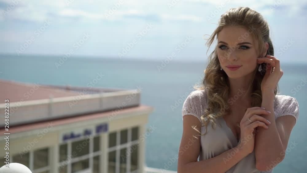 Young blonde woman in lingerie posing at terrace with sea view. Young blonde woman in lingerie posing at terrace with sea view.