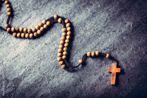 Wooden rosary laying on stone background.