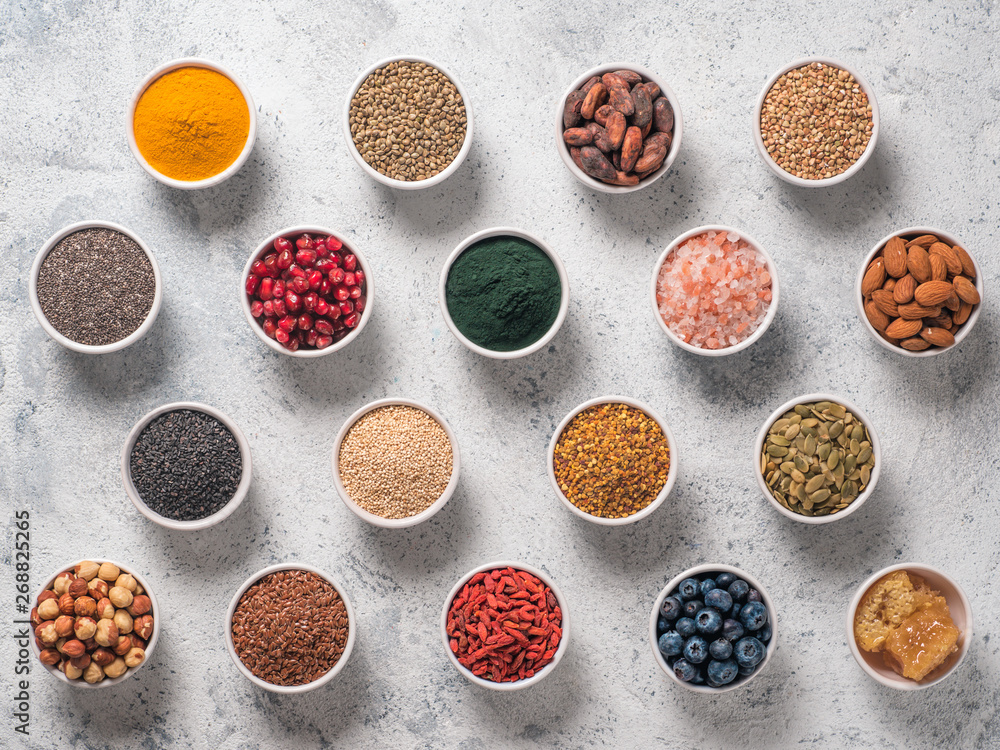 Various superfoods in smal bowl gray concrete background. Superfood as chia, spirulina, raw cocoa bean, goji, hemp, quinoa, bee pollen, black sesame, turmeric. Top view or flat-lay. Various superfoods in smal bowl gray concrete background. Superfood as chia, spirulina, raw cocoa bean, goji, hemp, quinoa, bee pollen, black sesame, turmeric. Top view or flat-lay.