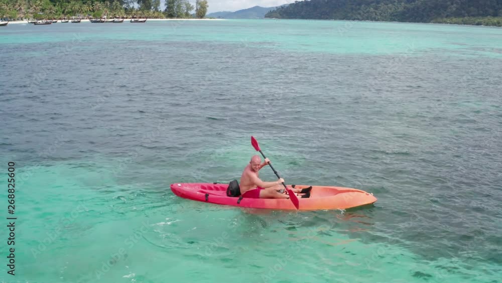 Aerial drone view of man kayaking in crystal clear lagoon sea water during summer day near Koh Kra island in Thailand. Travel tropical island holiday concept Aerial drone view of man kayaking in crystal clear lagoon sea water during summer day near Koh Kra island in Thailand. Travel tropical island holiday concept