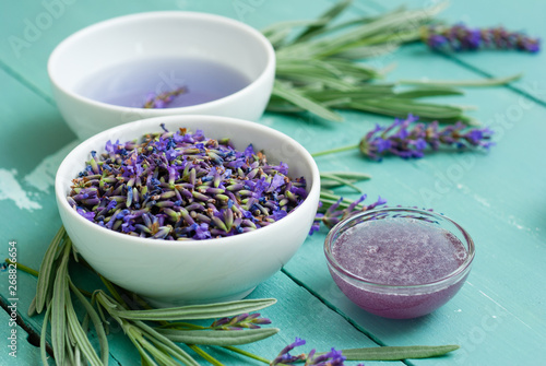 cup of lavender tea with a pile of fresh flowers  syrup  sugar candy on blue wood table background