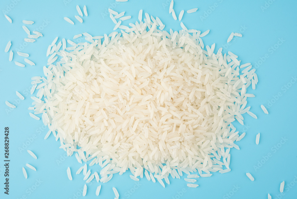 Pile white rice isolated on blue background on top view food object design
