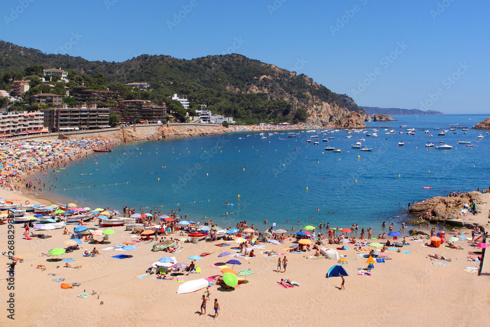 round bay in the blue sea and the beach where many people rest, faces are indistinguishable, travel concept