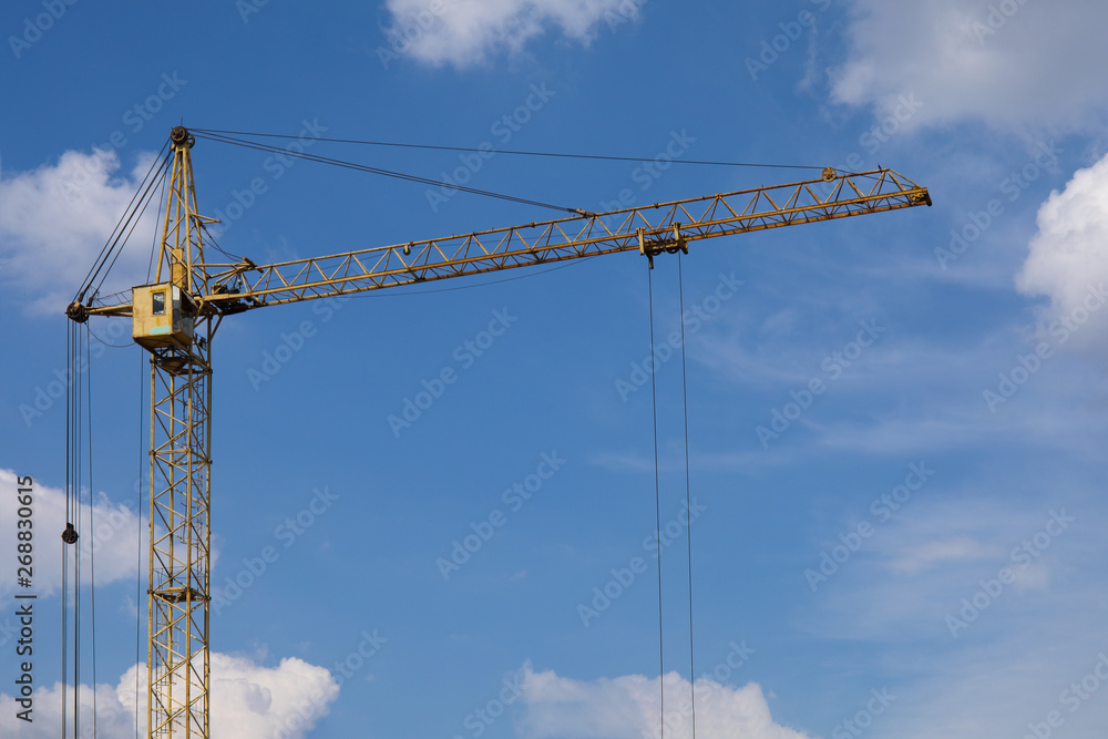 Industrial construction building crane against blue cloudy sky