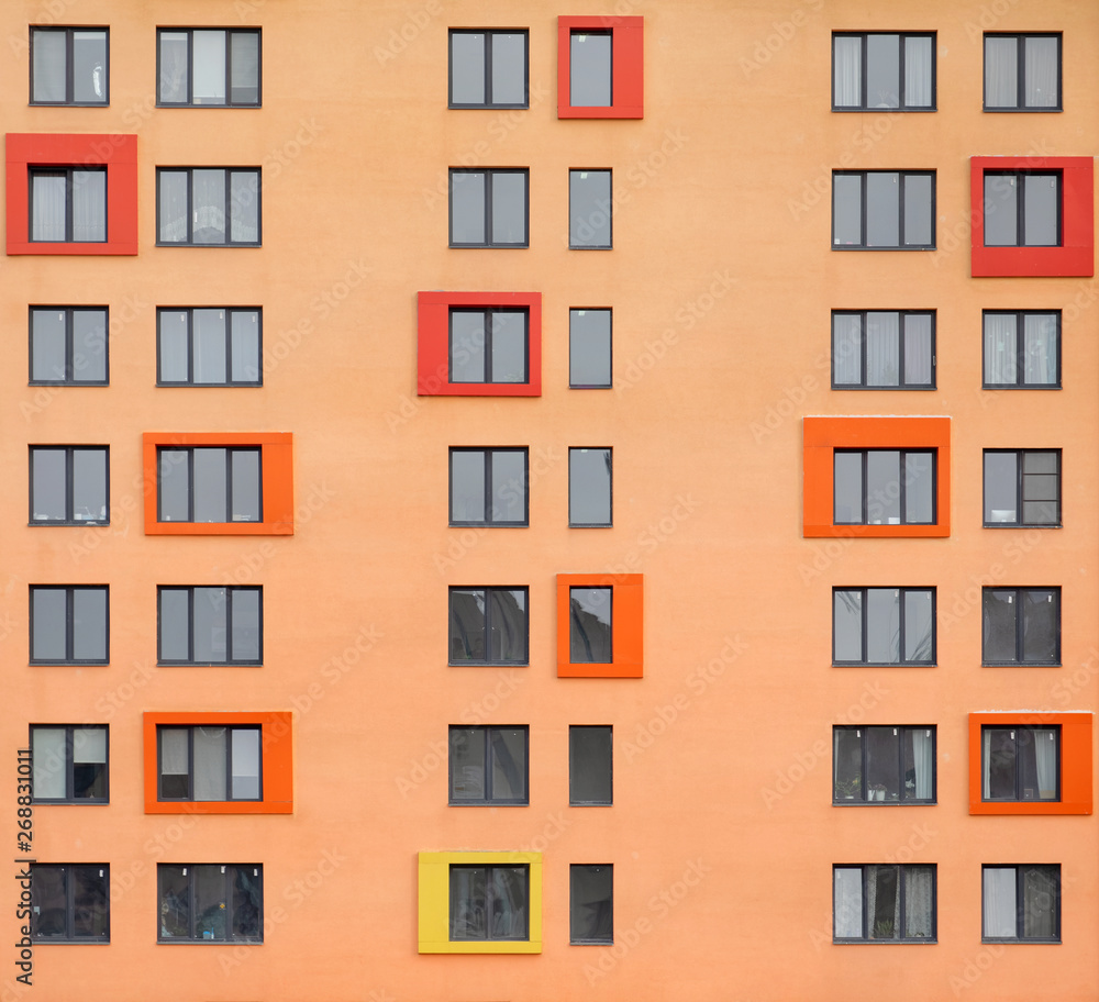 Many windows on the orange facade of the building. Architectural details in modern style