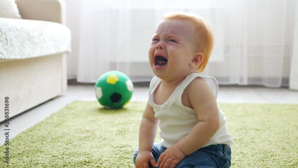 Crying redhead baby girl sitting on the floor Crying redhead baby girl sitting on the floor