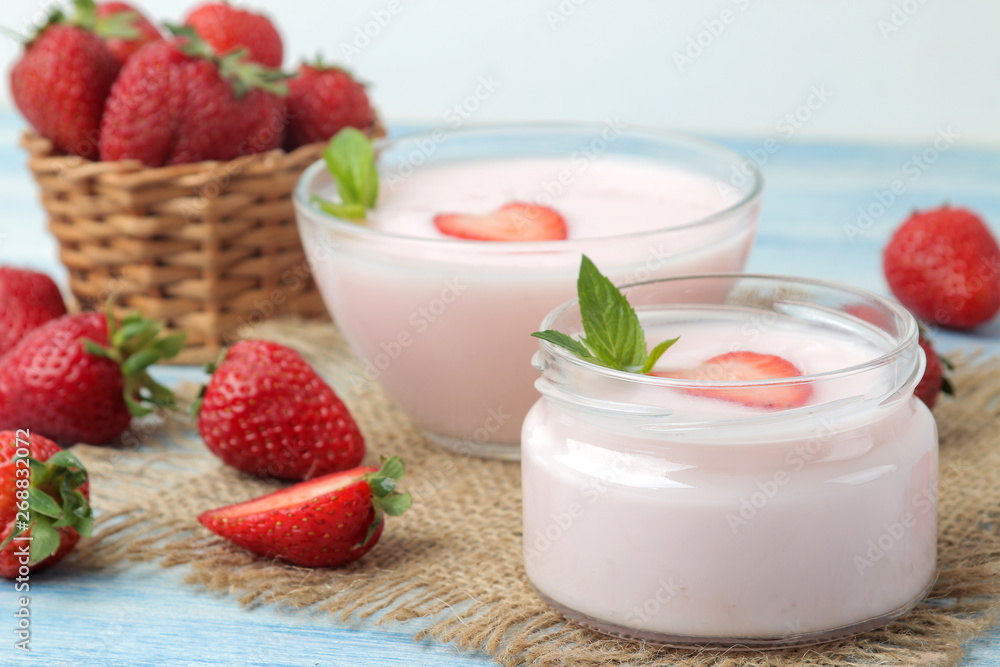 delicious strawberry yogurt in a jar and fresh ripe strawberries on a light blue wooden table. delicious strawberry yogurt in a jar and fresh ripe strawberries on a light blue wooden table.
