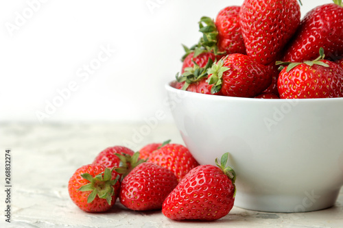 Ripe, delicious strawberries. Red strawberry in a ceramic bowl on a light concrete table. close-up