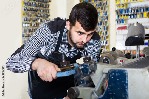 male worker shaping new key in repair workshop