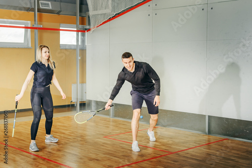 athletic man and woman playing squash.