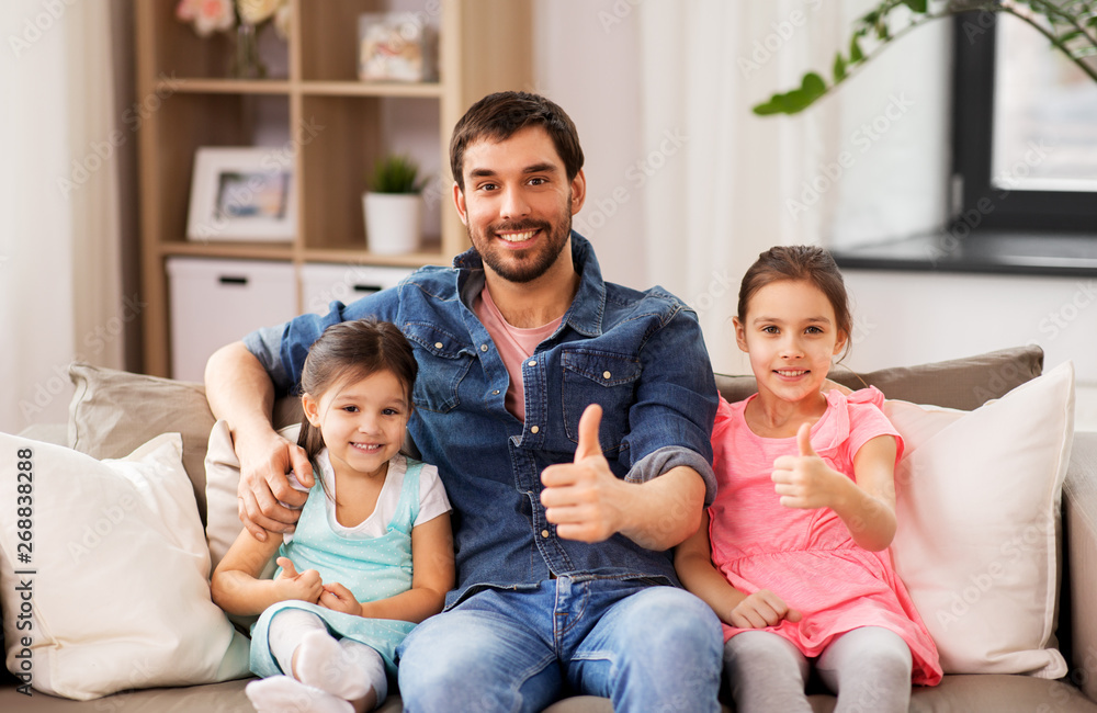 family, childhood and fatherhood concept - happy father with daughters showing thumbs up at home family, childhood and fatherhood concept - happy father with daughters showing thumbs up at home