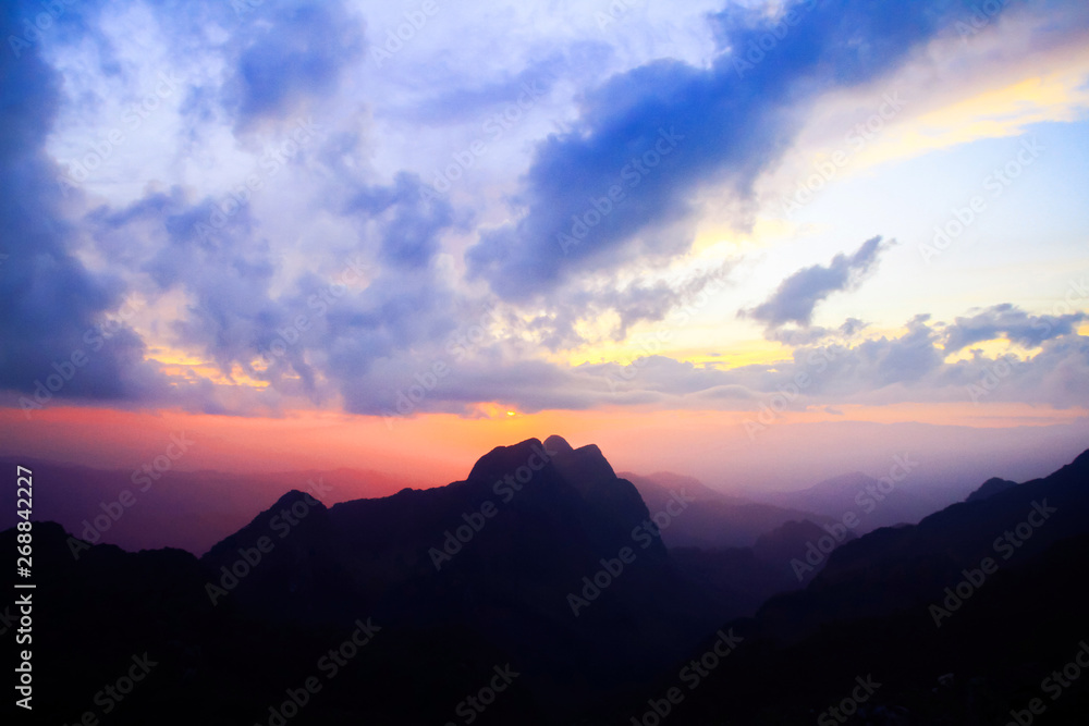 Obraz premium Sunset in sky and cloud, beautiful colorful twilight time with silhouette of mountain.