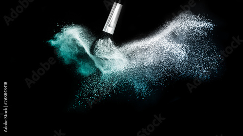 Cosmetic brush with blue cosmetic powder spreading for makeup artist and graphic design in black background